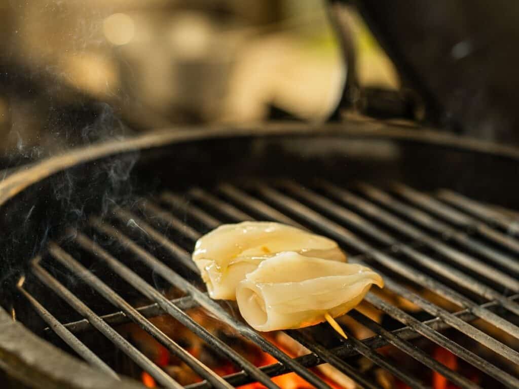 Squid cooking on the grill over glowing embers