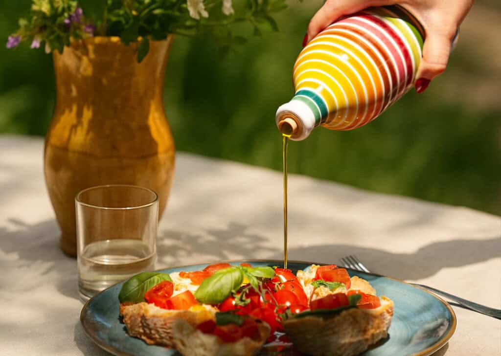 Tavola con pane casereccio, orcio in ceramica a righe e olio extravergine nuovo raccolto pronto per la degustazione